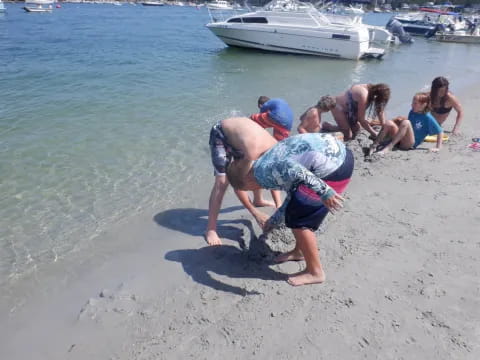 a group of people playing in the sand by the water