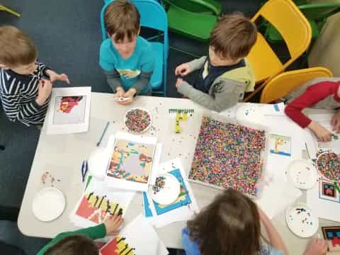 a group of children sitting around a table with a cake