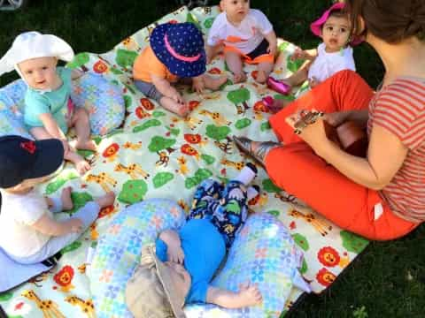 a person and several children sitting on a blanket