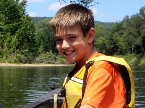 a boy in a life jacket in a boat on a lake