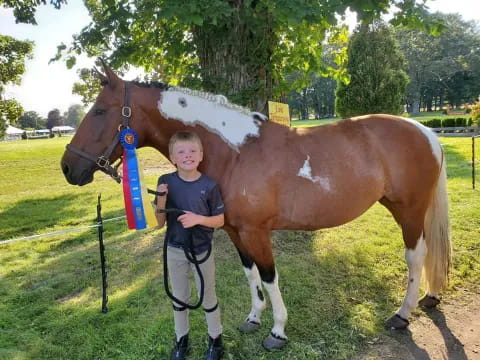 a boy standing next to a horse