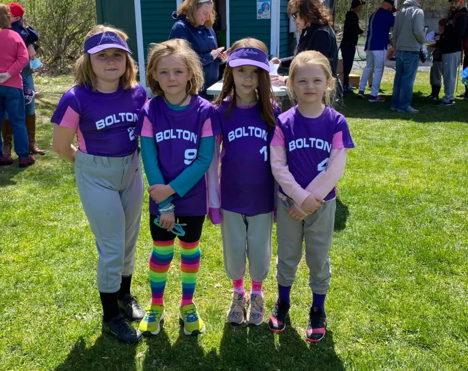 a group of girls in matching purple shirts standing on grass