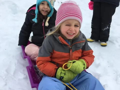 a couple of children in a sled in the snow