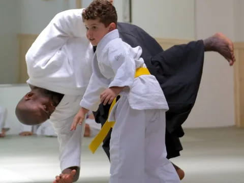 a man in white karate uniform kicking another man in the face