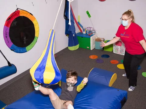 a person and a boy on a blue mat with a yellow and blue flag and balloons