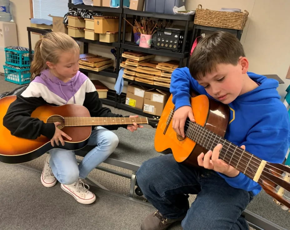 a boy and girl playing guitars