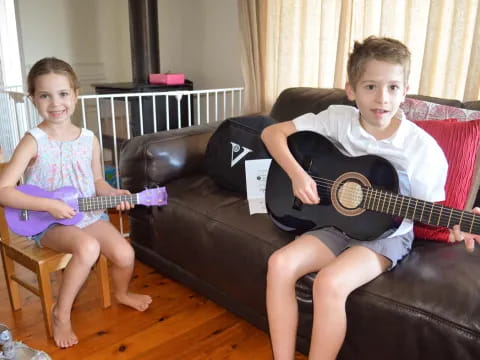 a boy and girl sitting on a couch playing a guitar