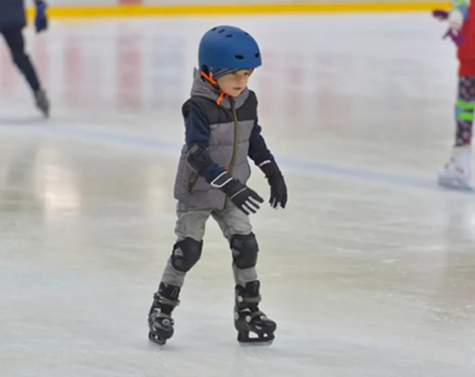 a young boy wearing a helmet and ice skates