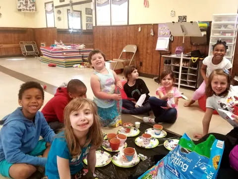 a group of children sitting on the floor eating food