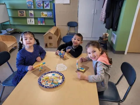a group of children sitting at a table with a cake