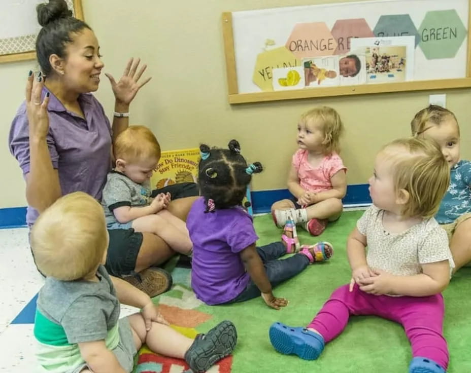 a person and several children sitting on the floor with a person in a bear garment