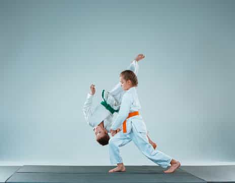 a man and a woman in karate uniforms jumping in the air