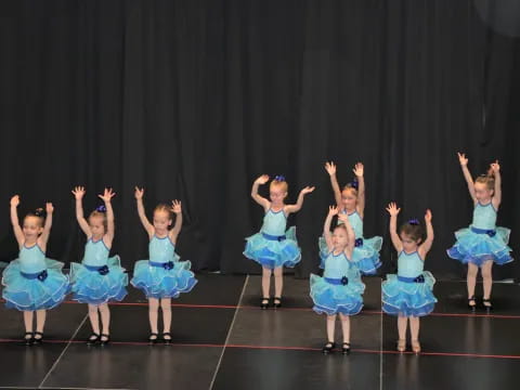 a group of girls in blue dresses dancing on a stage