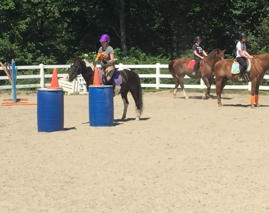 people riding horses in a dirt arena