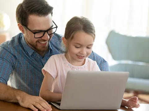 a person and a girl looking at a laptop
