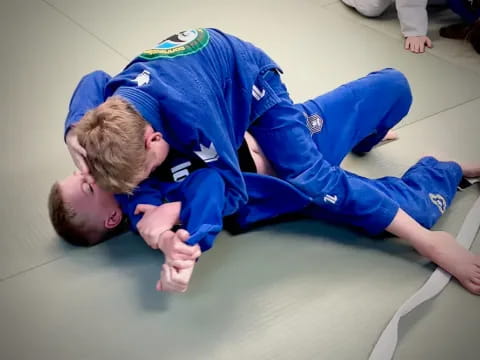 a man and a boy in blue uniforms on a blue mat