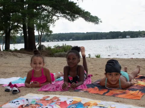 a group of children sitting on a blanket on a beach