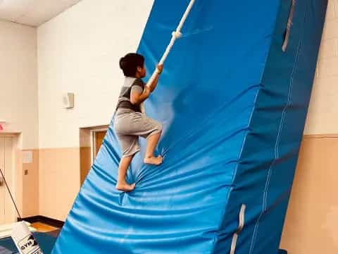 a boy climbing a blue tent