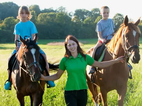 a person and two children riding horses