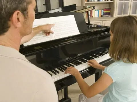 a man and a girl playing piano