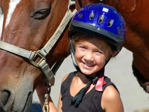 a girl smiling next to a horse