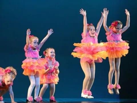 a group of girls in colorful dresses on a stage