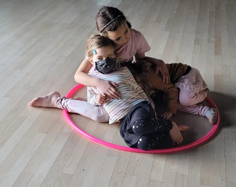 a man and woman sitting on a pink mat with a child on it