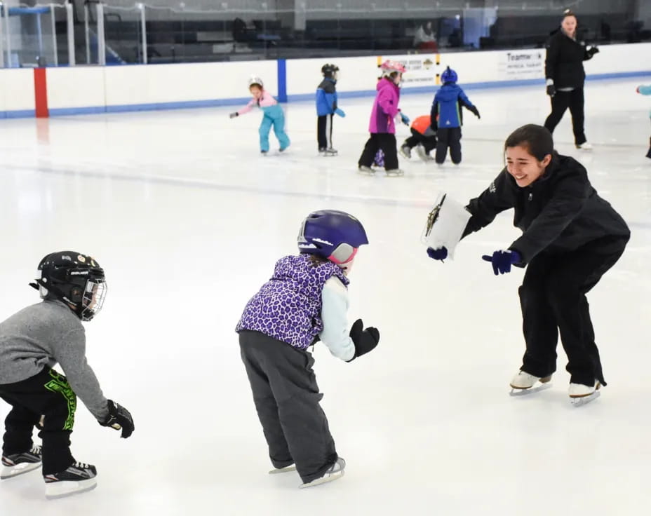 a person and a couple of kids on an ice rink with an audience