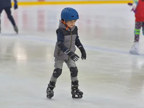 a young boy wearing a helmet and ice skates