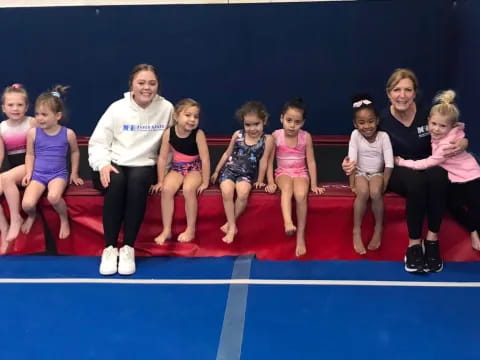 a group of people sitting on a mat posing for the camera