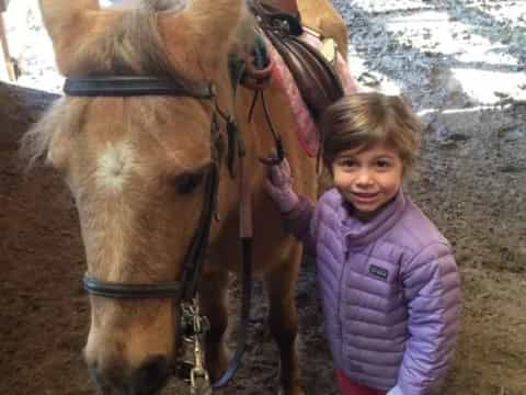 a girl standing next to a horse