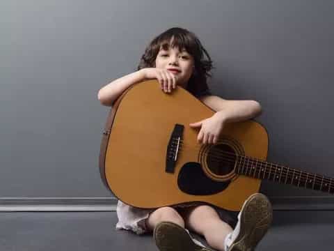 a girl sitting on the floor playing a guitar