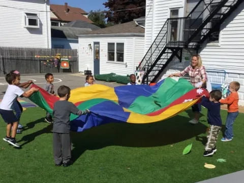 a group of kids playing with a large colorful kite