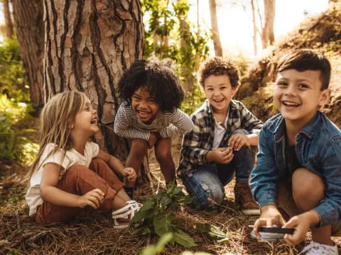 a group of children sitting next to a tree