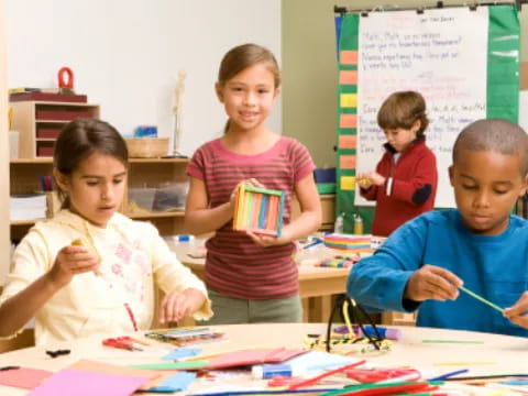 a group of children sitting at a table with colored pencils
