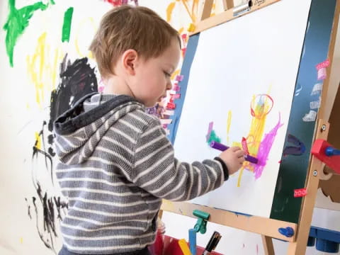 a young boy painting on a white board