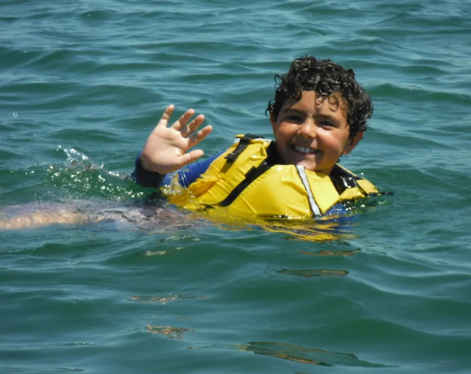 a boy in a life jacket on a surfboard