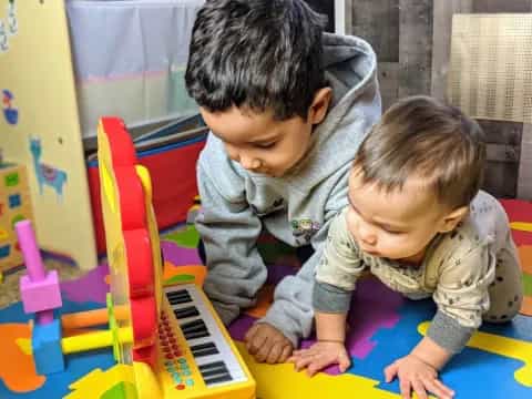 a couple of children playing with a toy piano