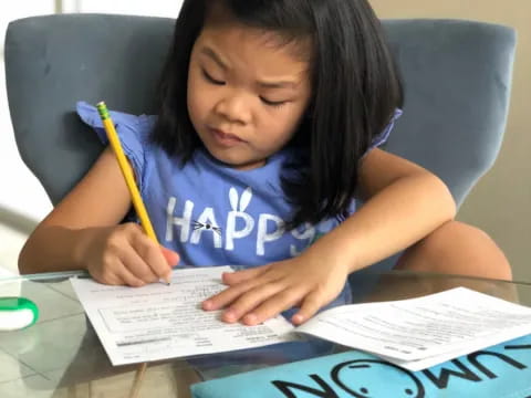 a young girl writing on a piece of paper