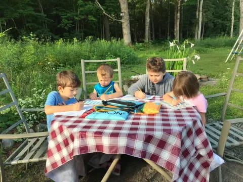 a group of kids sitting around a table outside