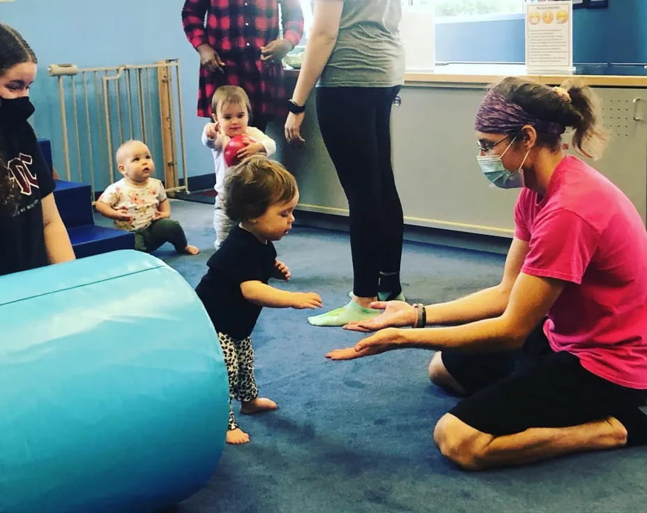 a person and a couple of children playing on a blue mat