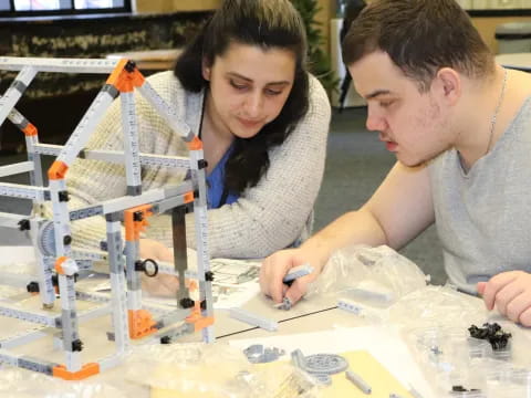 a man and a woman working on a model of a space ship