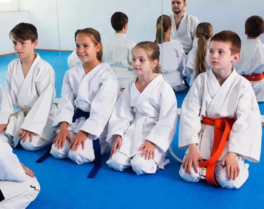 a group of people in white karate uniforms sitting on the floor