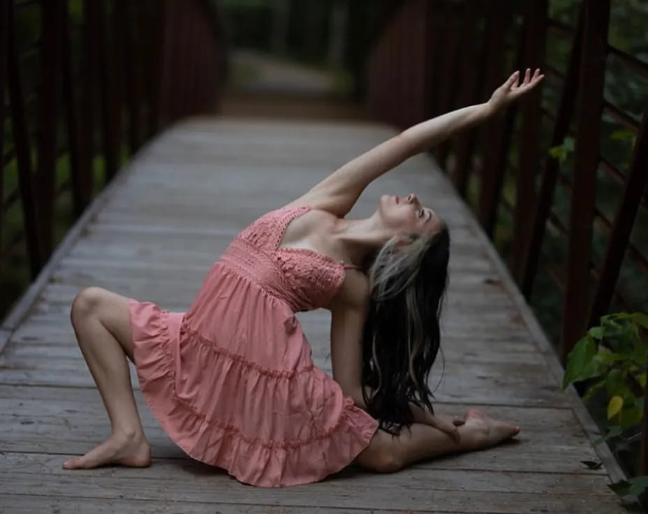 a person in a pink dress doing yoga on a wooden deck