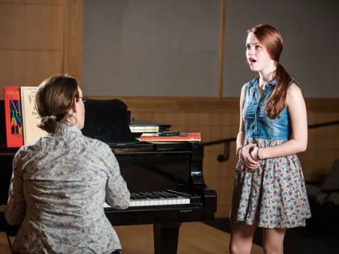 a person standing next to a person playing a piano