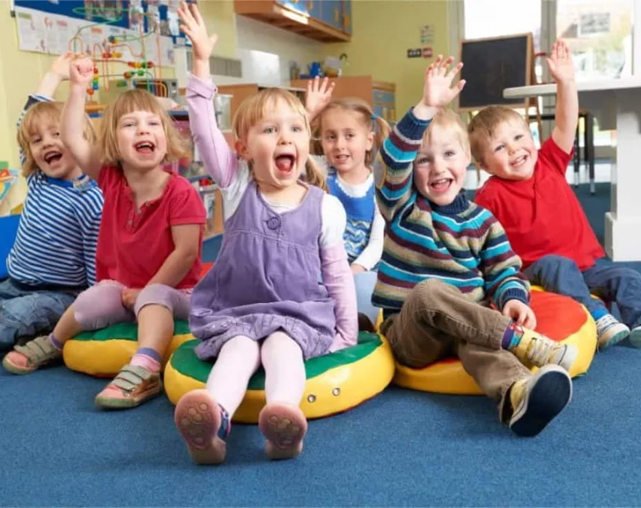 a group of children sitting on a yellow and green mat