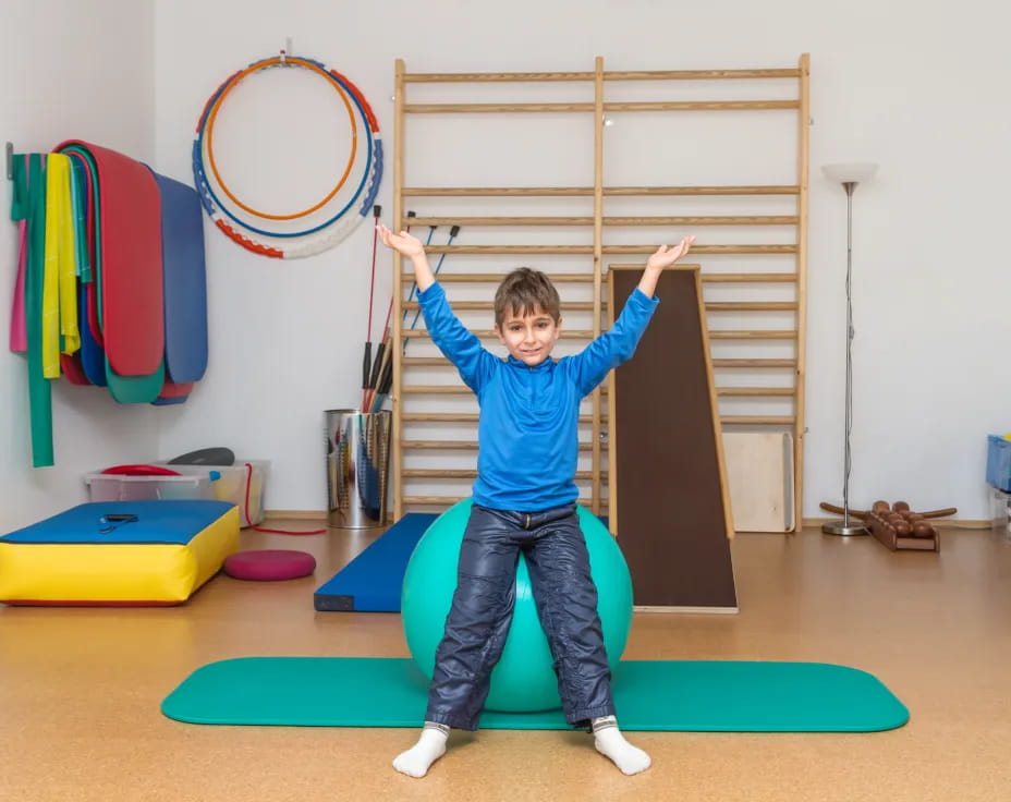 a boy standing on a mat in a room with a play set