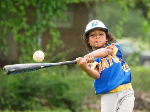 a young girl swinging a baseball bat