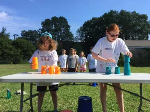 a group of people standing around a table with cups on it