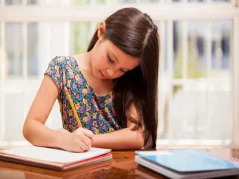 a young girl writing on a book